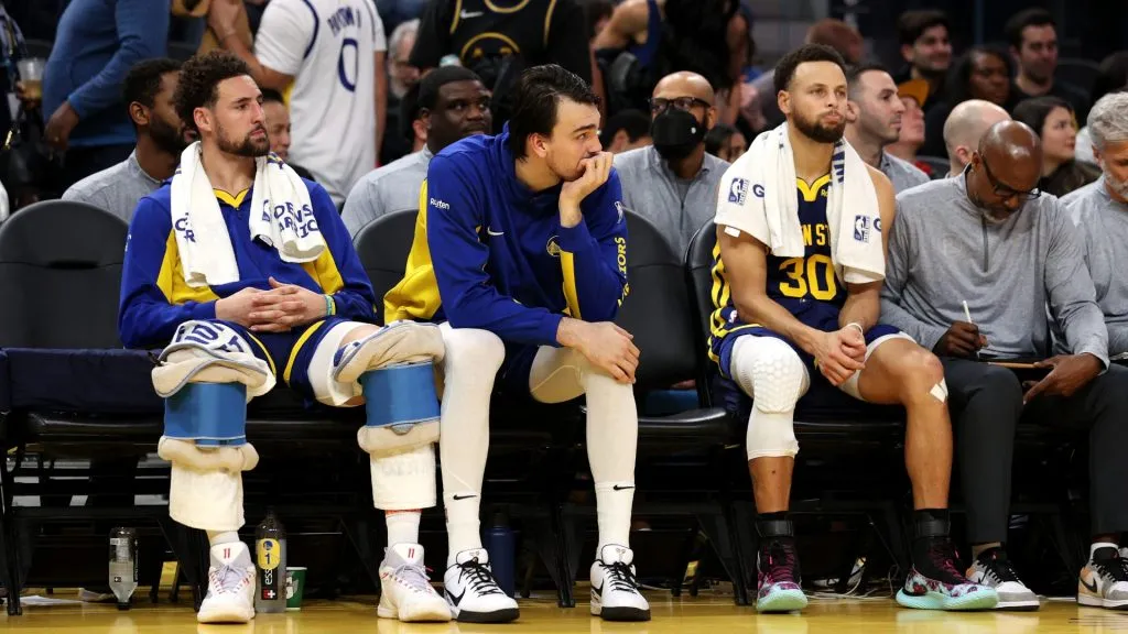 Klay Thompson #11, Dario Saric #20 and Stephen Curry #30 of the Golden State Warriors sit on the bench during the closing minutes of their loss to the Miami Heat in the second half at Chase Center on December 28, 2023 in San Francisco, California. (Photo by Ezra Shaw/Getty Images)