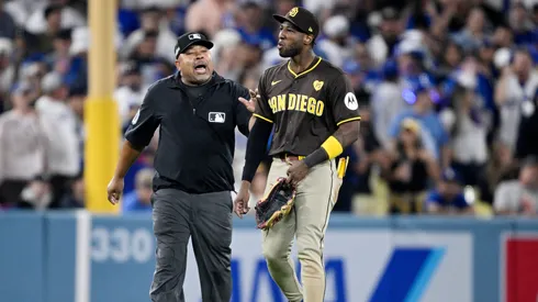 Jurickson Profar #10 of the San Diego Padres walks across the field escorted by umpire Adrian Johnson after an incident with fans in the seventh inning against the Los Angeles Dodgers during Game Two of the Division Series at Dodger Stadium on October 06, 2024 in Los Angeles, California. (Photo by Orlando Ramirez/Getty Images)