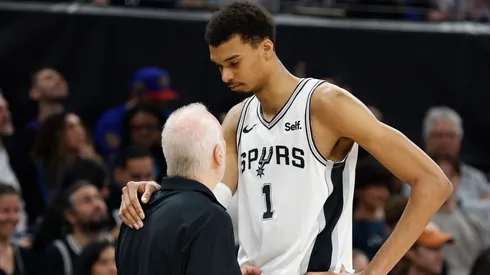 Victor Wembanyama #1 of the San Antonio Spurs is consoled by head coach Gregg Popovich of the San Antonio Spurs during a game against the Denver Nuggets in the first half at Moody Center on March 15, 2024 in Austin, Texas.