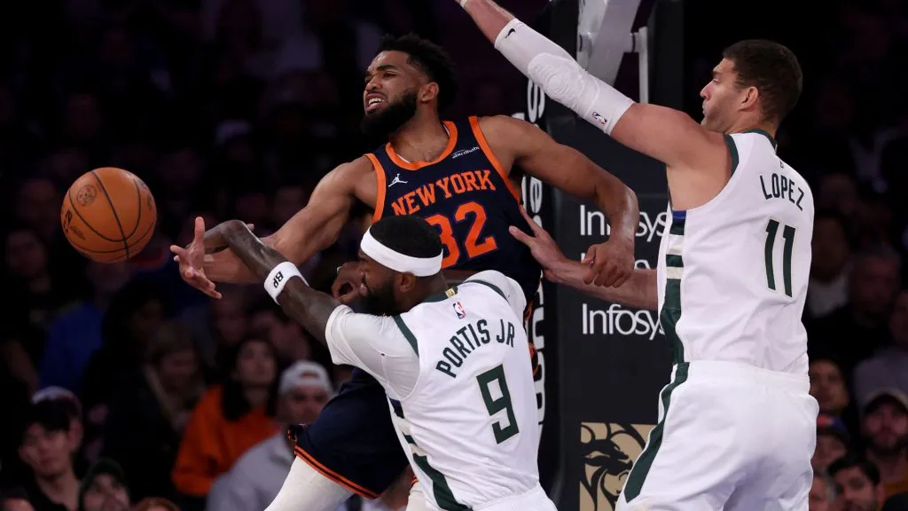 Karl-Anthony Towns #32 of the New York Knicks passes the ball under pressure from Bobby Portis #9 and Brook Lopez #11 of the Milwaukee Bucks at Madison Square Garden. Elsa/Getty Images