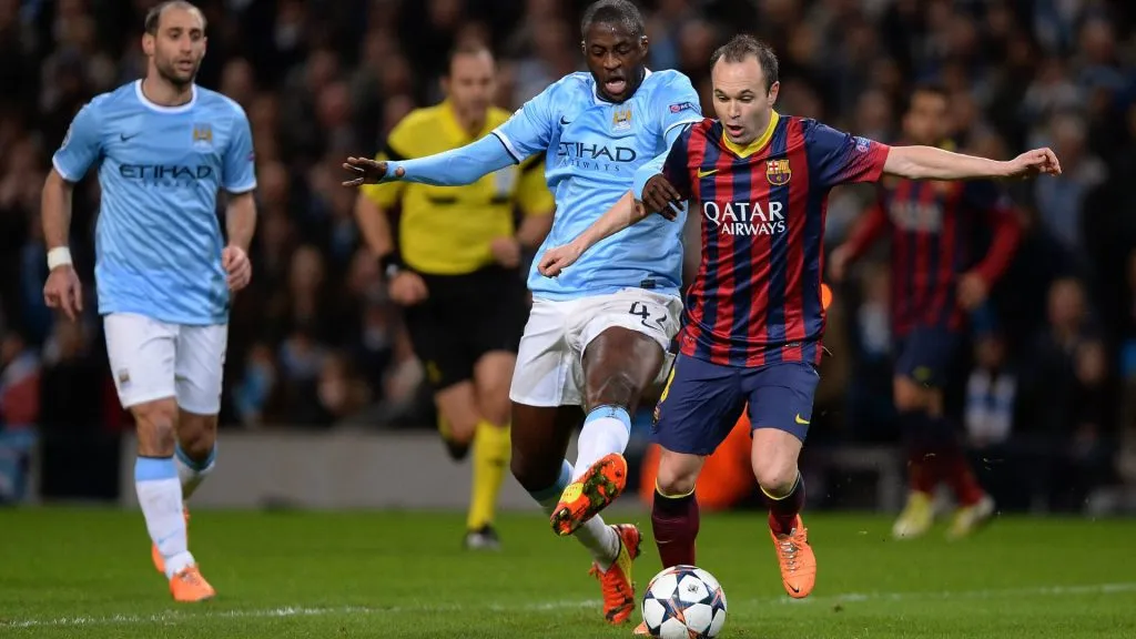 Yaya Toure tries to get the ball away from Andres Iniesta in a UEFA Champions League match between Manchester City and Barcelona.