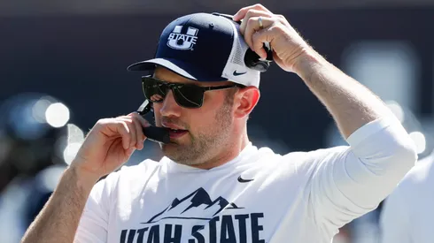 Interim head coach Nate Dreiling of the Utah State Aggies talks on his headset during the first half of their game against the Utah Utes at Maverik Stadium on September 14, 2024 in Logan, Utah.
