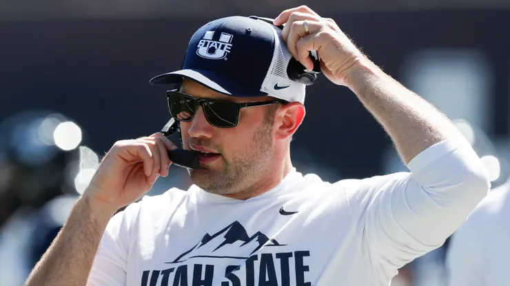 Interim head coach Nate Dreiling of the Utah State Aggies talks on his headset during the first half of their game against the Utah Utes at Maverik Stadium on September 14, 2024 in Logan, Utah.