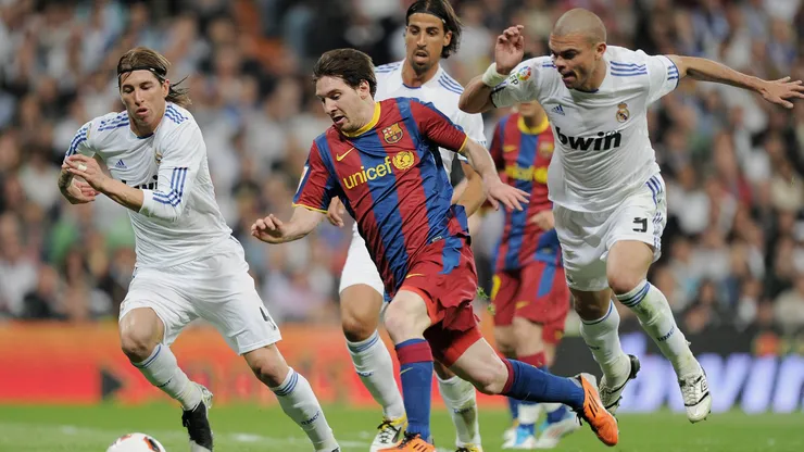 Lionel Messi from Barcelona dribbles the ball against Sergio Ramos, Sami Khedira and Pepe from Real Madrid.