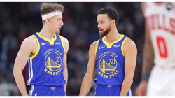 Brandin Podziemski 2 of the Golden State Warriors chats with Stephen Curry 30 of the Golden State Warriors during the first half against the Chicago Bulls at the United Center on January 12, 2024 in Chicago, Illinois.
