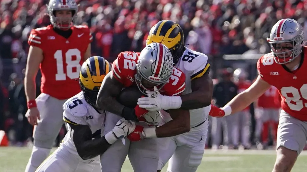 TreVeyon Henderson #32 of the Ohio State Buckeyes is tackled by Ernest Hausmann #15 and Cameron Brandt #91 of the Michigan Wolverines during the first quarter at Ohio Stadium on November 30, 2024 in Columbus, Ohio.