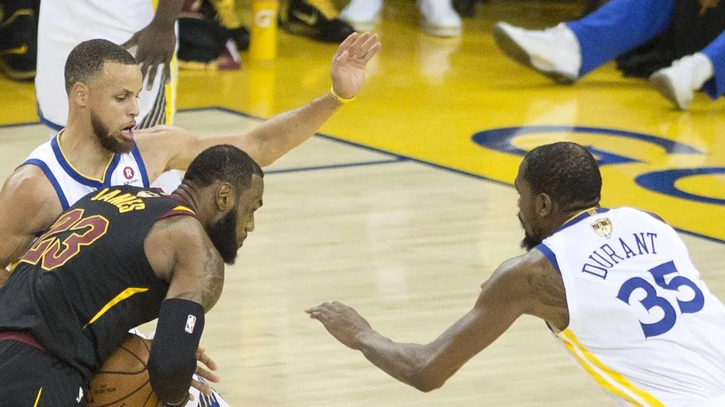 LeBron James 23 of the Cleveland Cavaliers drives against Stephen Curry 30 and Kevin Durant 35 of the Golden State Warriors