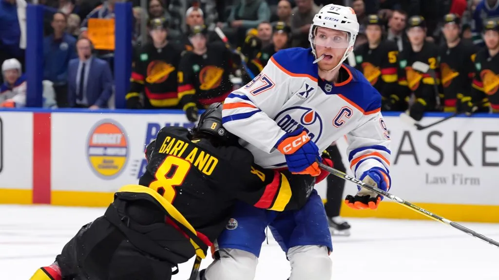 Connor McDavid #97 of the Edmonton Oilers is checked by Conor Garland #8 of the Vancouver Canucks during the third period of their NHL game at Rogers Arena on January 18, 2025 in Vancouver, British Columbia, Canada. 