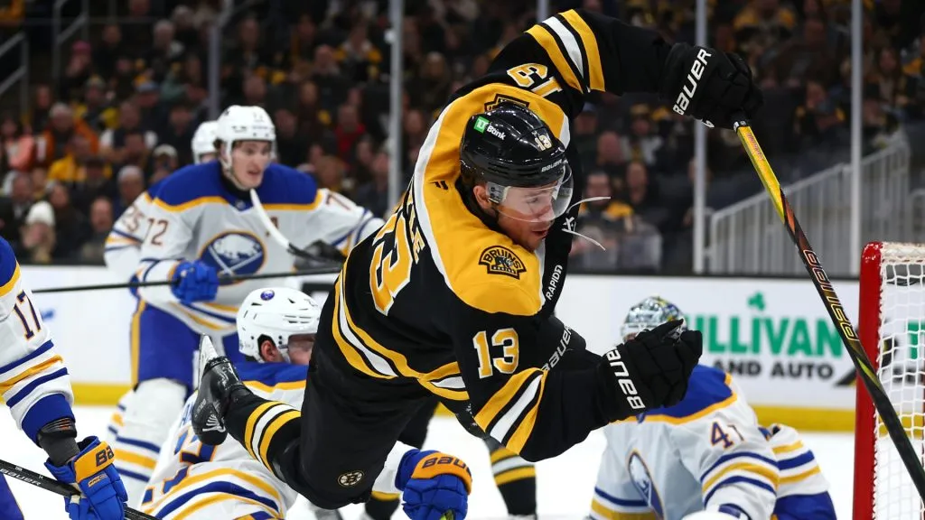 Charlie Coyle #13 of the Boston Bruins flies through the air in front of the goal defended by Jason Zucker #17 of the Buffalo Sabres during the third period at TD Garden on December 21, 2024 in Boston, Massachusetts. The Bruins defeat the Sabres 3-1.
