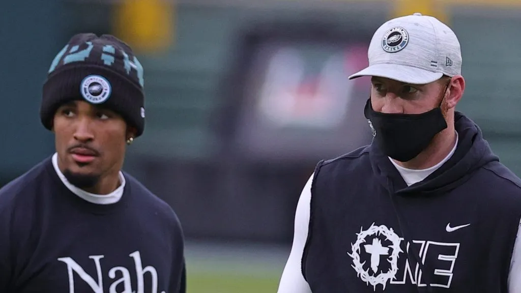 Jalen Hurts #2 and Carson Wentz #11 of the Philadelphia Eagles speak during warmups prior to a game against the Green Bay Packers at Lambeau Field on December 06, 2020 in Green Bay, Wisconsin. The Packers defeated the Eagles 30-16.