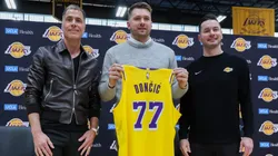 Luka Doncic (C) of the Los Angeles Lakers holds his new jersey while standing alongside general manager Rob Pelinka (L) and head coach JJ Redick.