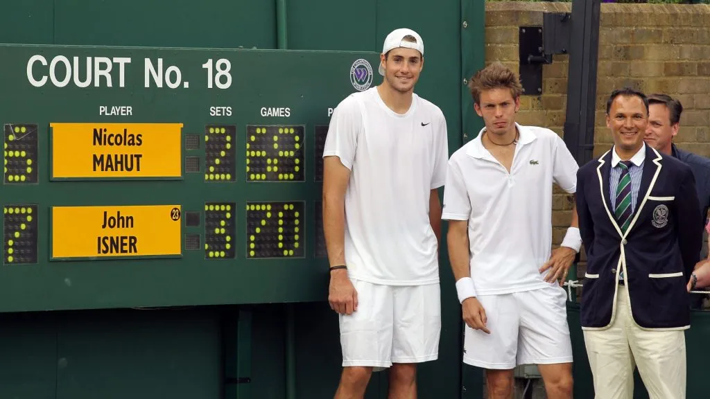John Isner poses after winning on the third day of his first round match against Nicolas Mahut with Chair Umpire Mohamed Lahyani on Day Four of the Wimbledon Lawn Tennis Championships in 2010. (Source: Hamish Blair/Getty Images)