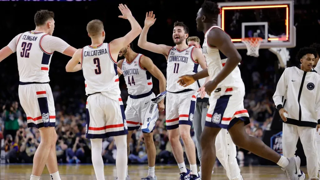 Alex Karaban and teammates celebrate a three-point basket at the end of the first half against the Miami Hurricanes during the NCAA Men’s Basketball Tournament Final Four semifinal game. (Source: Carmen Mandato/Getty Images)