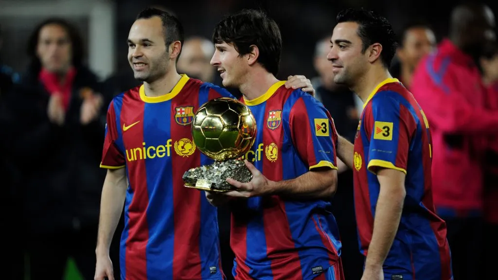 Lionel Messi of FC Barcelona (C) holds the Ballon d’Or trophy flanked by his teammates Andres Iniesta (L) and Xavi Hermandez. (David Ramos/Getty Images)