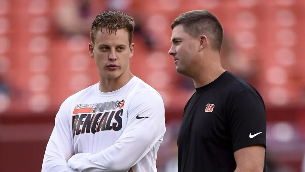 Joe Burrow #9 of the Cincinnati Bengals talks with head coach Zac Taylor before the NFL preseason game against the Washington Football Team at FedExField on August 20, 2021 in Landover, Maryland.