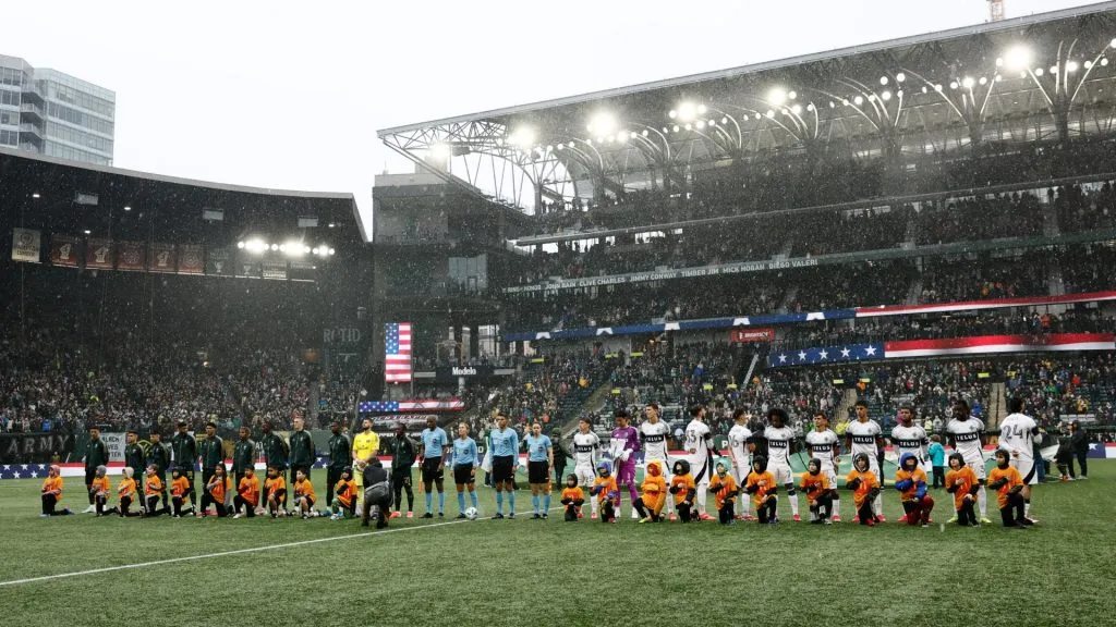 The Portland Timbers and the Vancouver Whitecaps stand on the pitch during the playing of the National Anthem before the game at Providence Park on February 23, 2025. (Source: Alika Jenner/Getty Images)