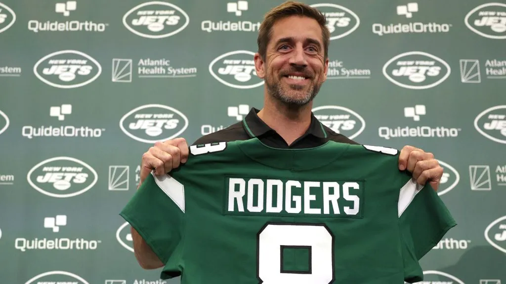 New York Jets quarterback Aaron Rodgers poses with a jersey during an introductory press conference in 2023. (Source: Elsa/Getty Images)