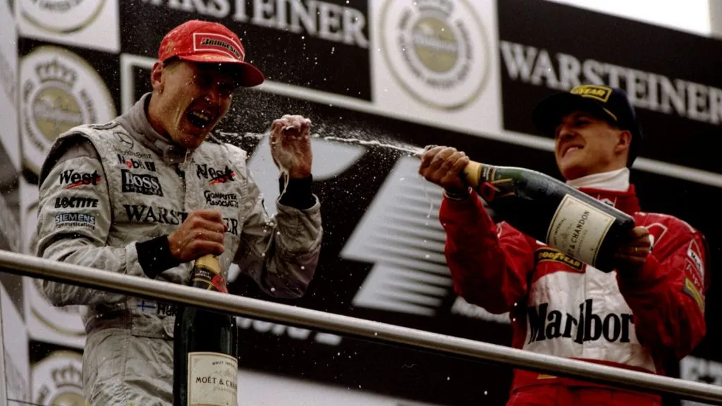 Mika Hakkinen is sprayed with champagne by championship rival Michael Schumacher after the Luxembourg Grand Prix in 1998 (Clive Mason /Allsport)