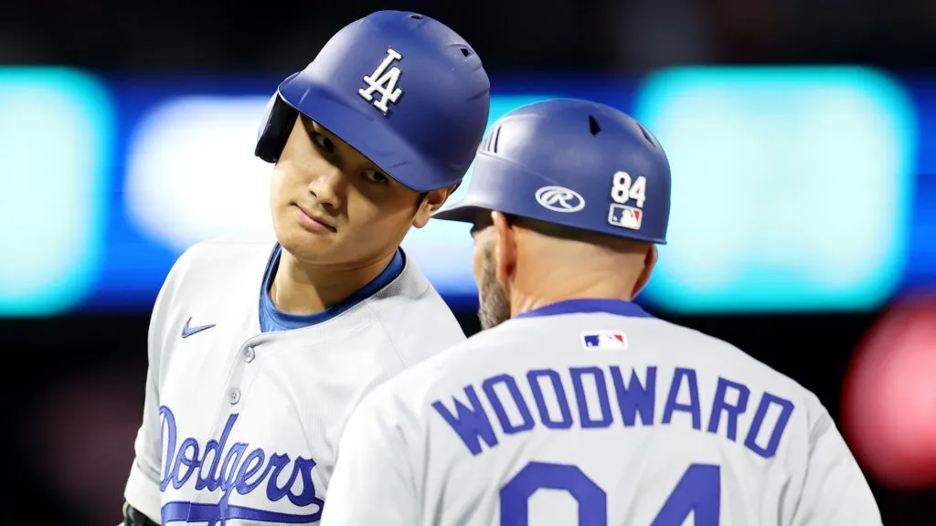 Shohei Ohtani #17 of the Los Angeles Dodgers celebrates a single with first base coach Chris Woodward #84
