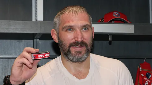 Alex Ovechkin #8 of the Washington Capitals poses with the puck used during his 895th career goal in the second period against the New York Islanders at UBS Arena on April 06, 2025 in Elmont, New York. Ovechkin's goal passes Wayne Gretzky's 894 goals to become the NHL all-time goal-scoring leader.