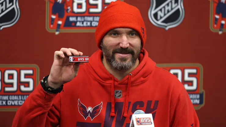 lex Ovechkin #8 of the Washington Capitals poses with the puck used during his 895th career goal in the second period against the New York Islanders at UBS Arena on April 06, 2025 in Elmont, New York. Ovechkin's goal passes Wayne Gretzky's 894 goals to become the NHL all-time goal-scoring leader.