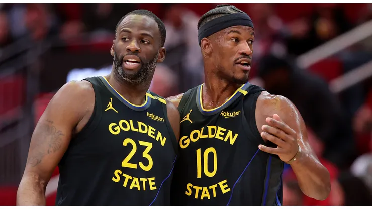 Draymond Green #23 and Jimmy Butler #10 of the Golden State Warriors speak on the court against the Houston Rockets during the first half at Toyota Center on February 13, 2025 in Houston, Texas.