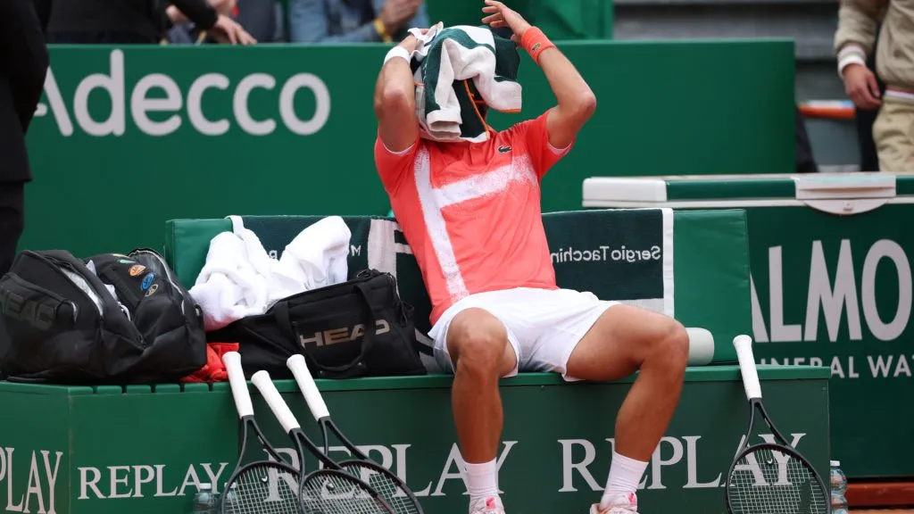 Novak Djokovic of Serbia dries his face with a towel whilst sat on his bench during a break at the change of ends during his match against Alejandro Tabilo. (Clive Brunskill/Getty Images)