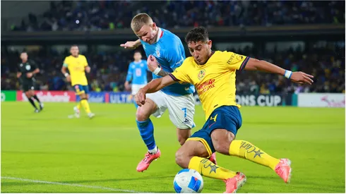 Mateusz Bogusz of Cruz Azul battles for possession with Sebastian Caceres of America