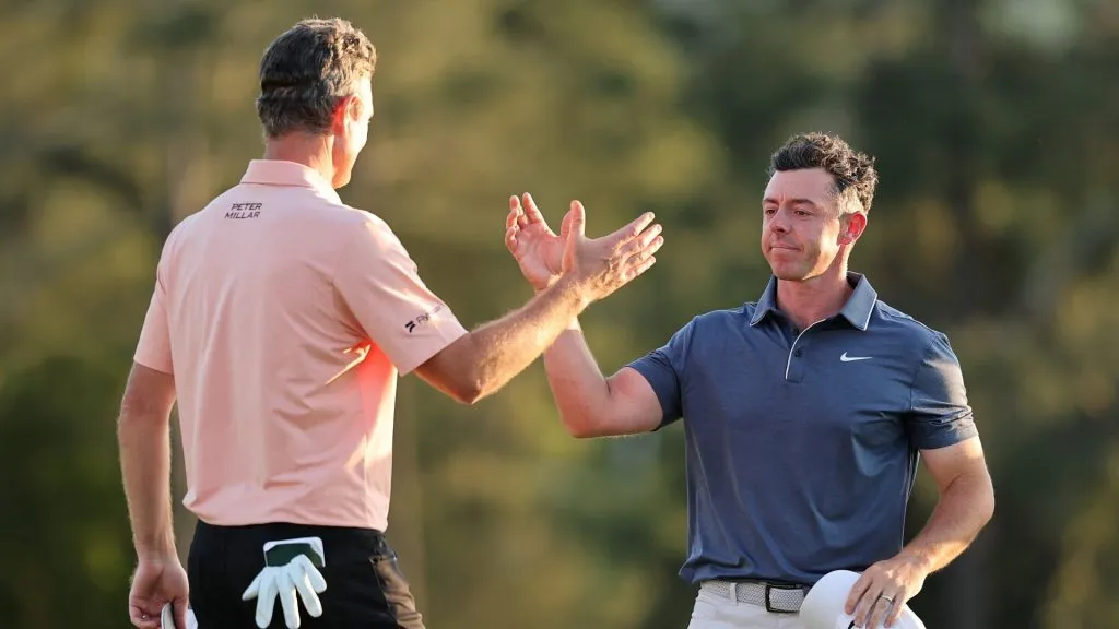 (R-L) Rory McIlroy of Northern Ireland embraces Justin Rose of England