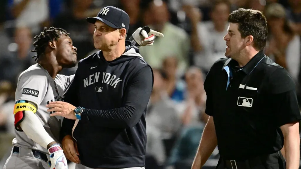 Jazz Chisholm Jr. #13 of the New York Yankees is held back by manager Aaron Boone #17 after an ejection