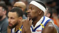 Jimmy Butler III #10 and Stephen Curry #30 of the Golden State Warriors watch from the bench during the second half of the NBA game against the Phoenix Suns at PHX Arena on April 08, 2025 in Phoenix, Arizona.