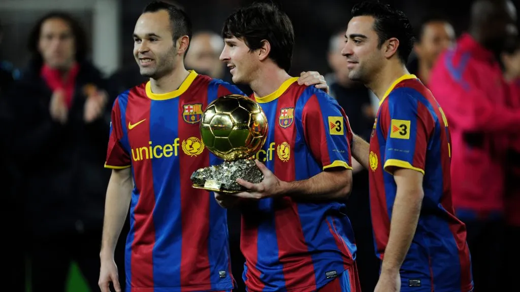Lionel Messi of FC Barcelona (C) holds the Ballon d’Or trophy flanked by his teammates Andres Iniesta (L) and Xavi Hermandez. (David Ramos/Getty Images)