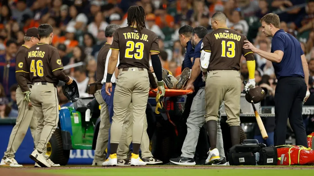 Fernando Tatis Jr. #23 and Manny Machado #13 of the San Diego Padres watch as Luis Arraez #4 of the San Diego Padres is loaded onto a cart after colliding with Mauricio Dubon in the first inning against the Houston Astros at Daikin Park on April 20, 2025 in Houston, Texas. (Photo by Tim Warner/Getty Images)