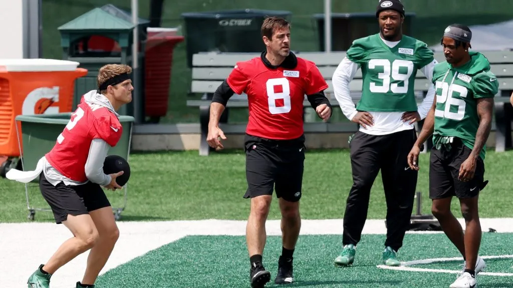 Aaron Rodgers #8 of the New York Jets reacts after a medicine ball warm up drill as Zach Wilson #2 works out during an offseason workout session at Atlantic Health Jets Training Center in 2023. (Source: Elsa/Getty Images)
