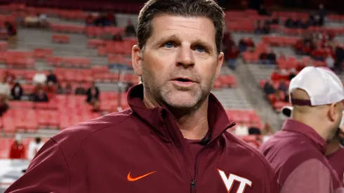 Head coach Brent Pry of the Virginia Tech Hokies talks with field judge Karina Tovar prior to the game against the North Carolina State Wolfpack at Carter-Finley Stadium on October 27, 2022 in Raleigh, North Carolina.