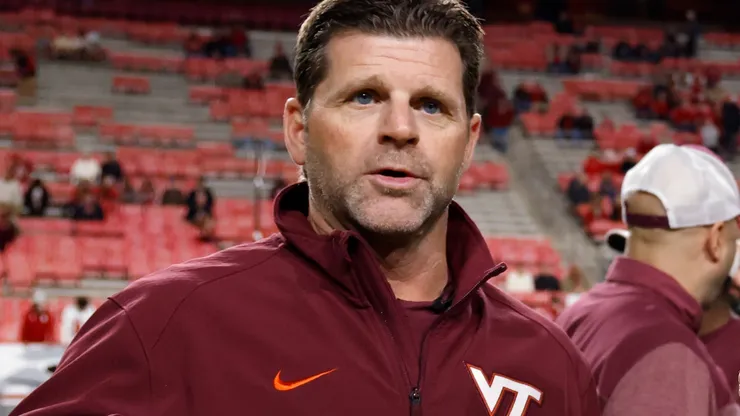 Head coach Brent Pry of the Virginia Tech Hokies talks with field judge Karina Tovar prior to the game against the North Carolina State Wolfpack at Carter-Finley Stadium on October 27, 2022 in Raleigh, North Carolina.
