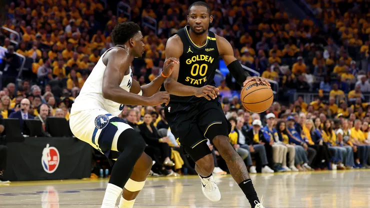 Jonathan Kuminga #00 of the Golden State Warriors dribbles the ball against Anthony Edwards #5 of the Minnesota Timberwolves.