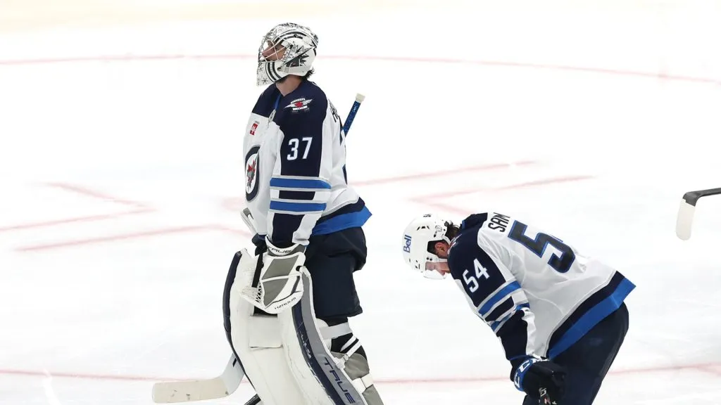 Connor Hellebuyck #37 and Neal Pionk #4 of the Winnipeg Jets react after being defeated by the Dallas Stars in overtime to lose Game Six of the Second Round of the 2025 Stanley Cup Playoffs at American Airlines Center on May 17, 2025 in Dallas, Texas.