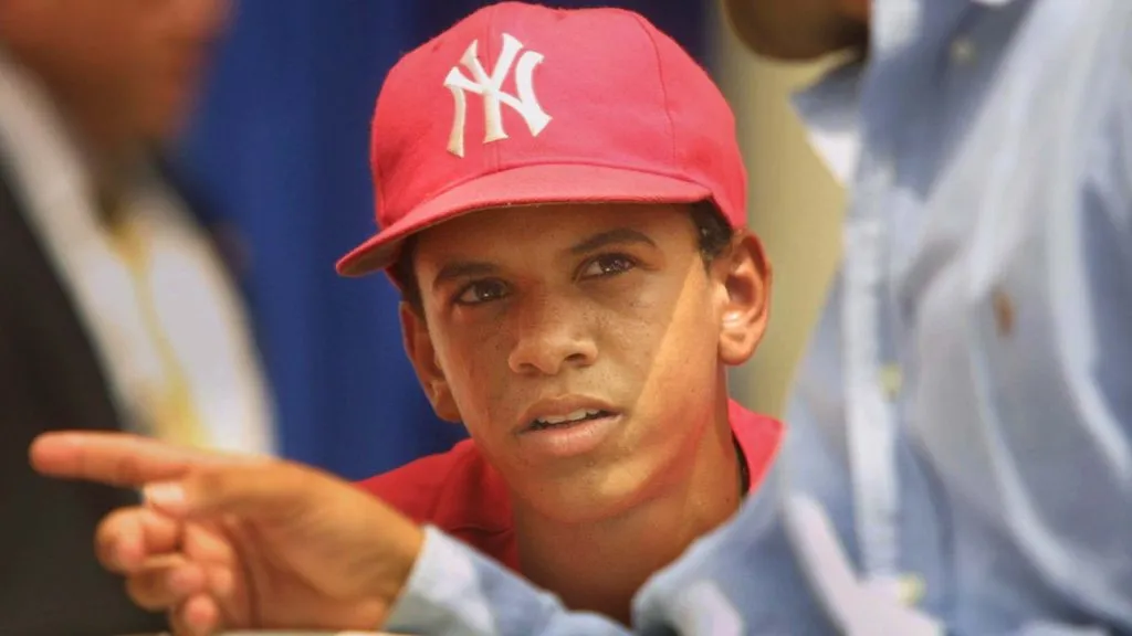 Danny Almonte of the Rolando Paulino All-Stars Bronx Little League baseball team looks at coach Rolando Paulino during a ceremony honoring the team August 28, 2001. (Source: Mario Tama/Getty Images)