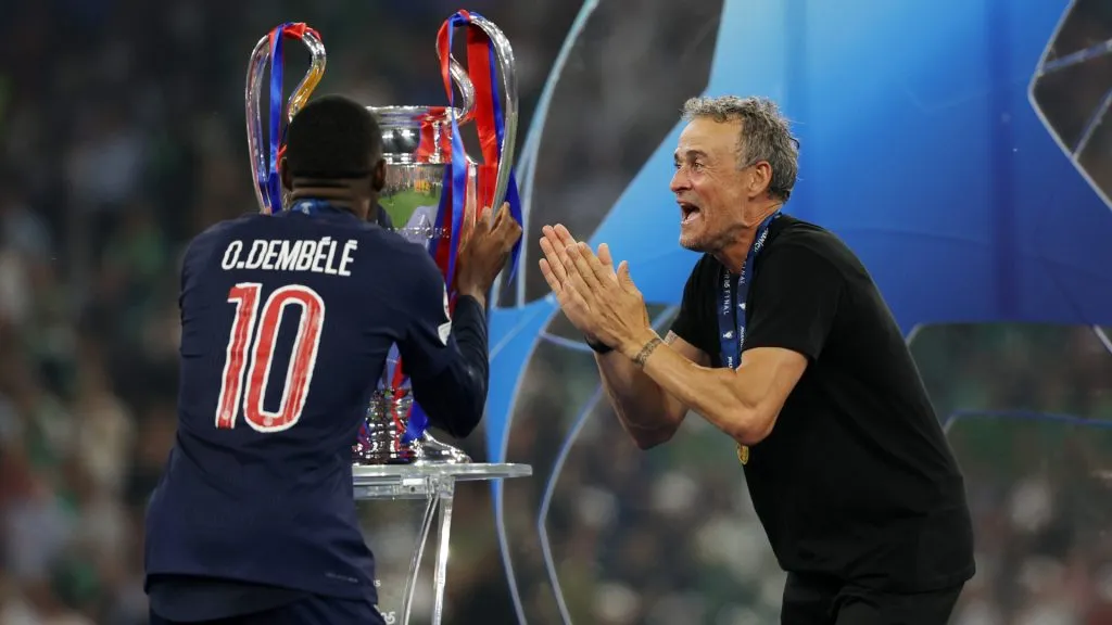 Ousmane Dembele of Paris Saint-Germain kisses the UEFA Champions League trophy, as Luis Enrique celebrates after their team’s victory. (Carl Recine/Getty Images)