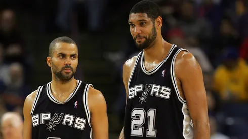 Tim Duncan #21 and Tony Parker #9 of the San Antonio Spurs stand on the court during their game against the Golden State Warriors on December 16, 2009.
