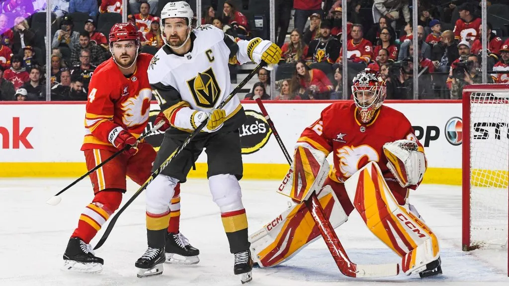 Rasmus Andersson #4 and Dustin Wolf #32 of the Calgary Flames defend net against Mark Stone #61 of the Vegas Golden Knights during the second period of an NHL game at Scotiabank Saddledome on April 5, 2025 in Calgary, Alberta, Canada. (Photo by Derek Leung/Getty Images)