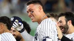 Aaron Judge #99 of the New York Yankees celebrates with teammates after hitting a walk-off sacrifice fly ball during the tenth inning against the Seattle Mariners at Yankee Stadium.
