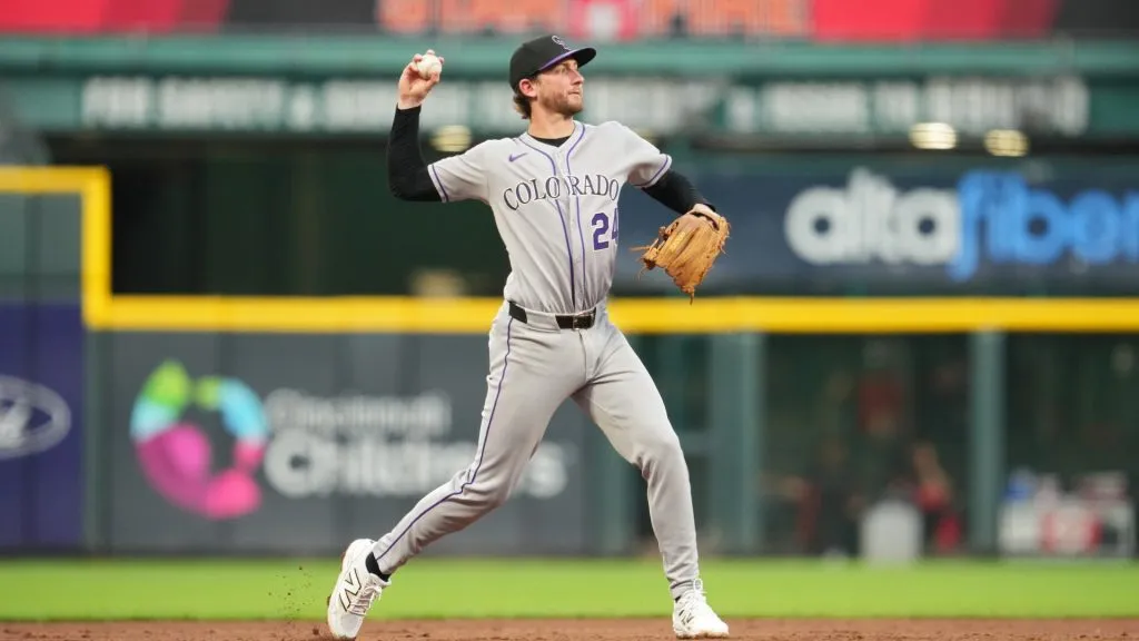 Ryan McMahon #24 of the Colorado Rockies throws Spencer Steer #7 of the Cincinnati Reds out at first base