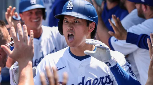 Shohei Ohtani #17 of the Los Angeles Dodgers reacts with teammates in the dugout after hitting a two-run home run to notch his 1000th MLB career.