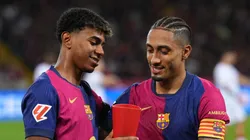 Raphinha of FC Barcelona presents teammate Lamine Yamal with the Player of the Month trophy