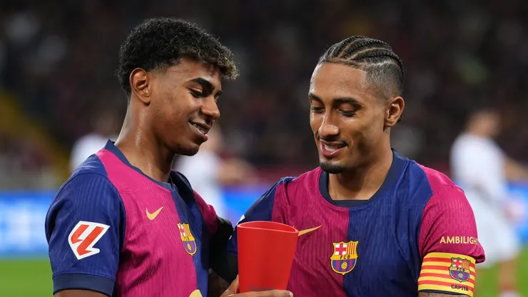 Raphinha of FC Barcelona presents teammate Lamine Yamal with the Player of the Month trophy