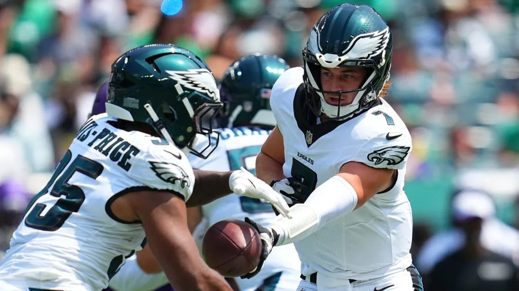 Eagles star Kenny Pickett handing a ball to Tyrion Davis-Price