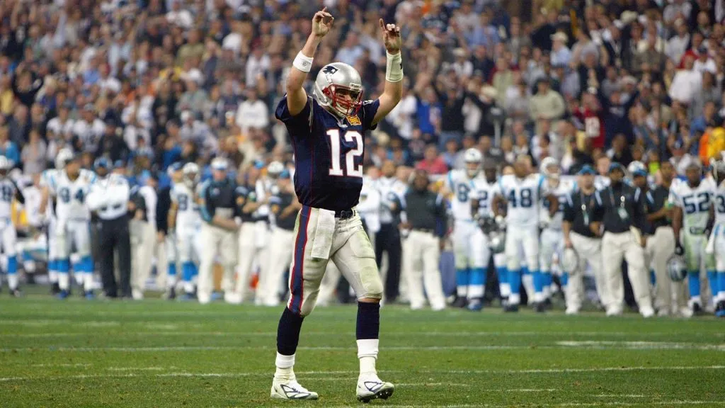 Quarterback Tom Brady #12 of the New England Patriots raises his arms in celebration of a play against the Carolina Panthers during Super Bowl XXXVIII in 2004. (Source: Andy Lyons/Getty Images)