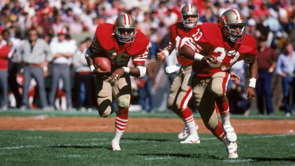 Wendell Tyler runs behind the protection of teammate running back Roger Craig #33 during a game against the Atlanta Falcons at Candlestick Park on September 30, 1984. (Source: George Rose/Getty Images)